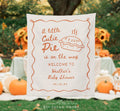 Baby shower backdrop with pie illustration and text in an outdoor setting with pumpkins and decorations.