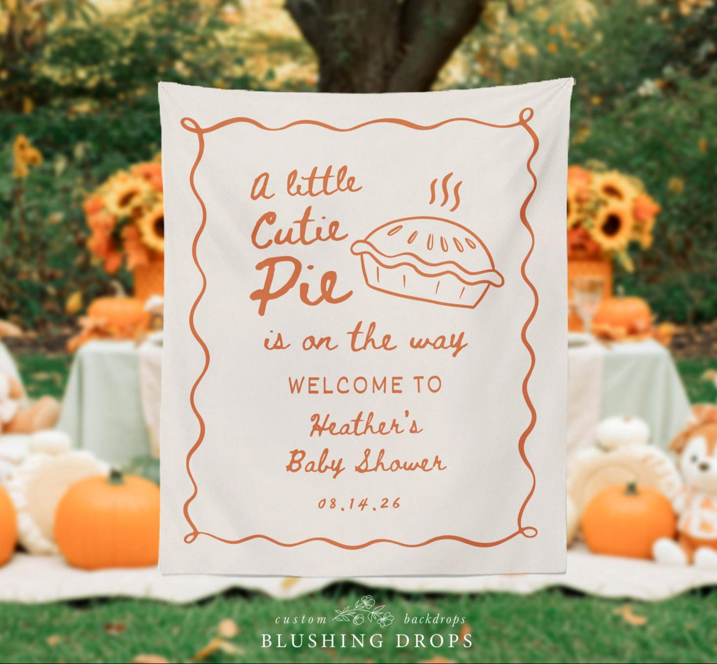 Baby shower backdrop with pie illustration and text in an outdoor setting with pumpkins and decorations.